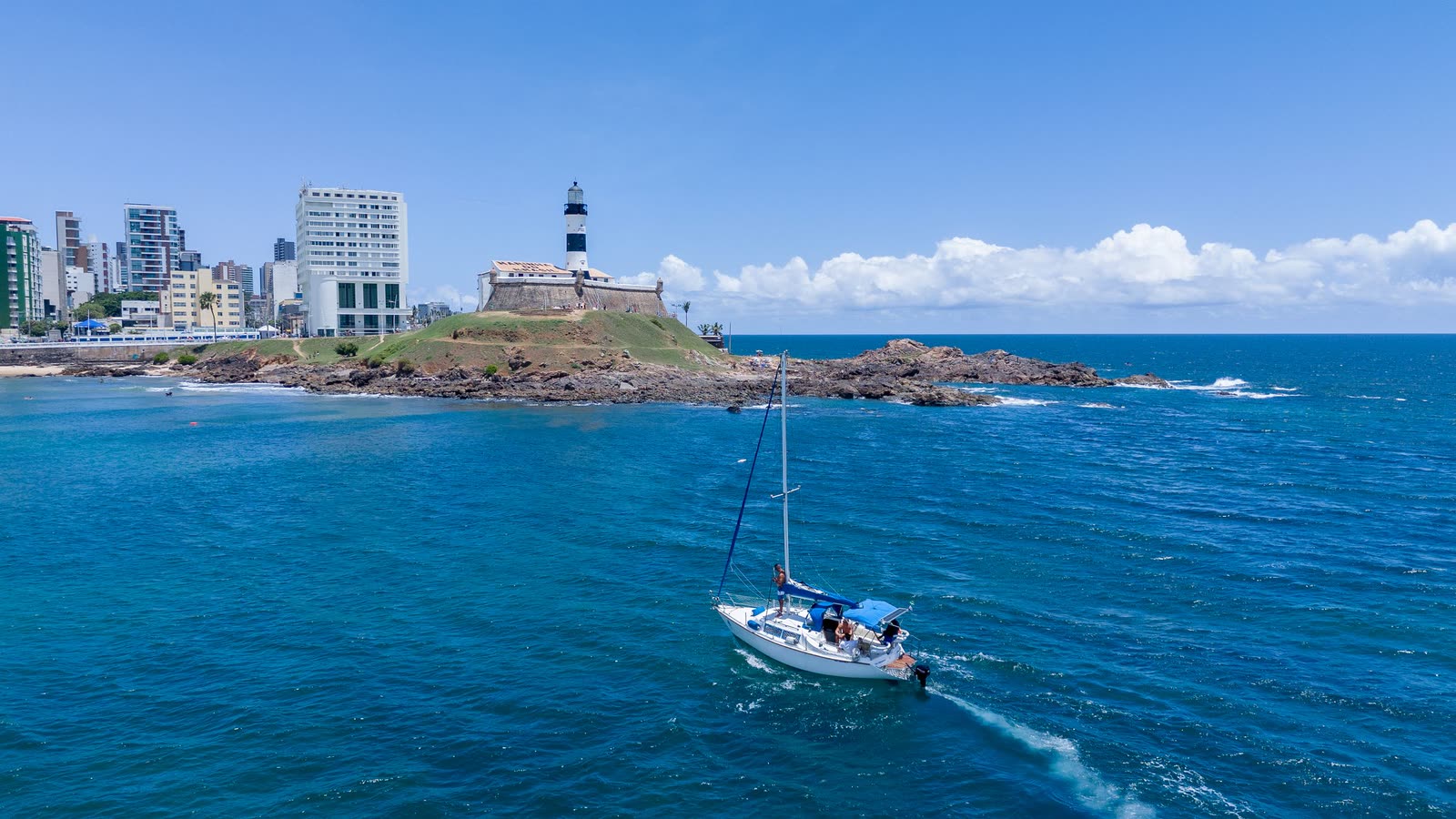 Veleiro passando em frente ao Farol da Barra