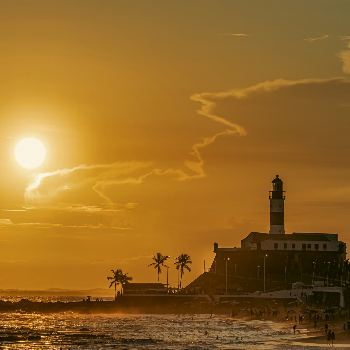 Pôr do sol dourado atrás do Farol da Barra